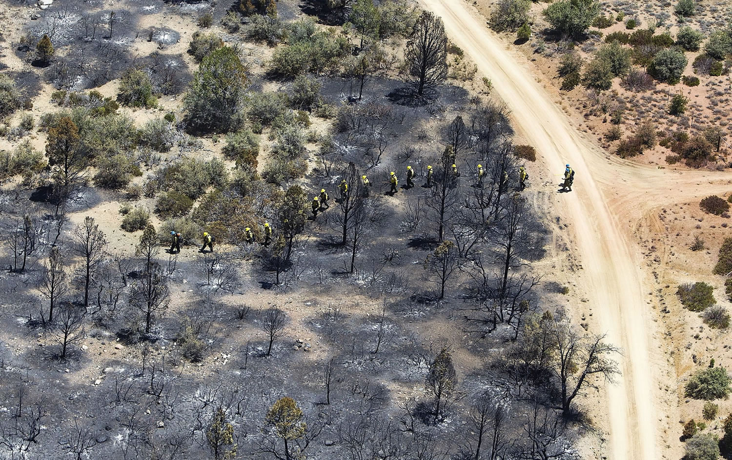 Firefighters walk across scorched land in Yarnell, Ariz., on Wednesday in the aftermath of the Yarnell Hill Fire that claimed the lives of 19 members of an elite firefighting crew on Sunday.