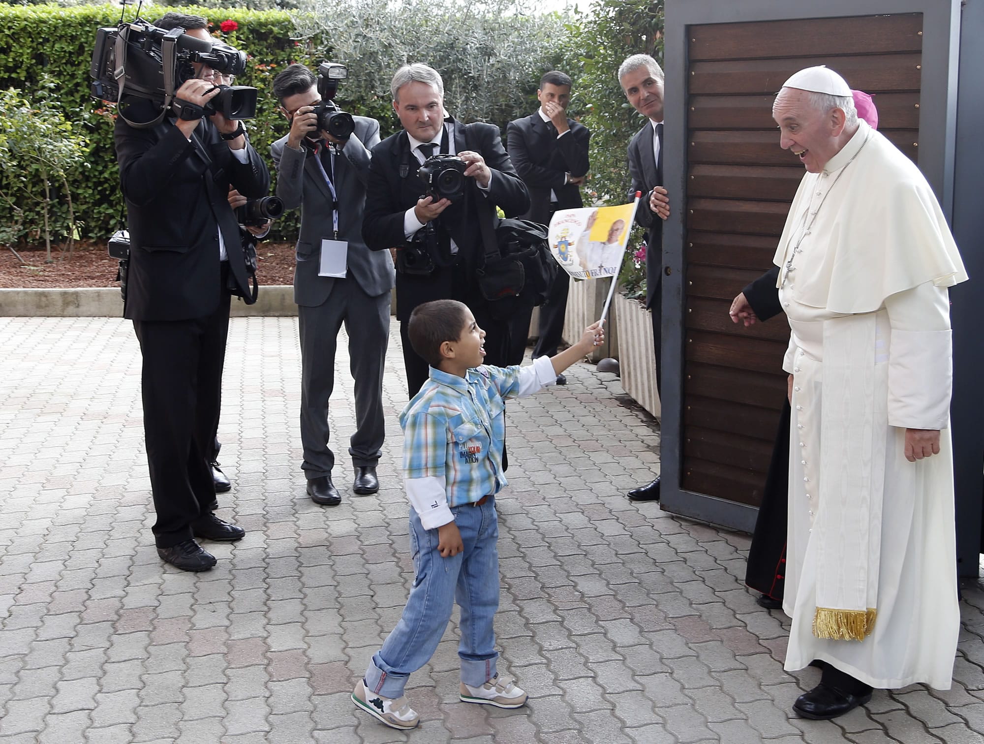 A child waves a flag as Pope Francis arrives Friday at Caritas Residence in Assisi, Italy.