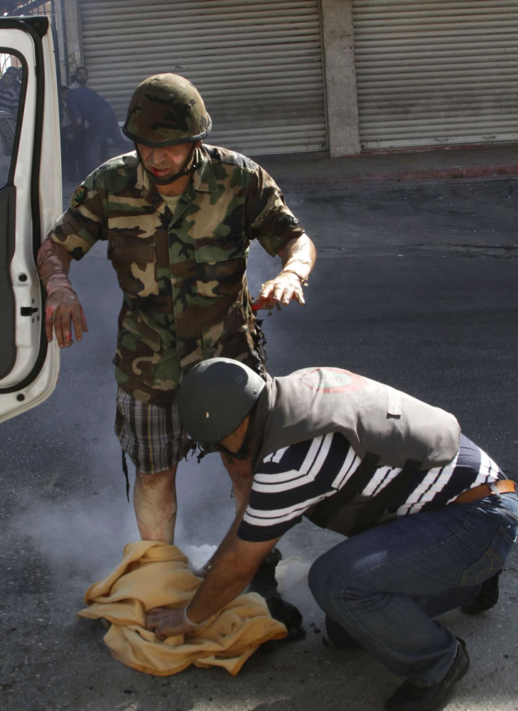 A medic helps an injured Lebanese soldier after his body caught on fire during clashes between followers of radical Sunni cleric Sheik Ahmad al-Assir and Shiite gunmen in the southern port city of Sidon, Lebanon, on Sunday.