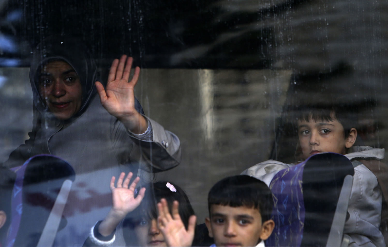 A Syrian refugee family waves to relatives after boarding a bus to Beirut International Airport for a flight to Germany where they have been accepted for temporary resettlement, at the International Organization for Migration office in Beirut, Lebanon on Thursday.