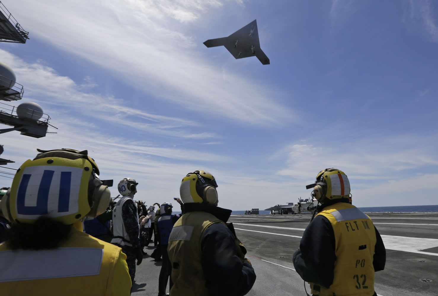 A Navy X-47B drone flies over the aircraft carrier USS George H. W.