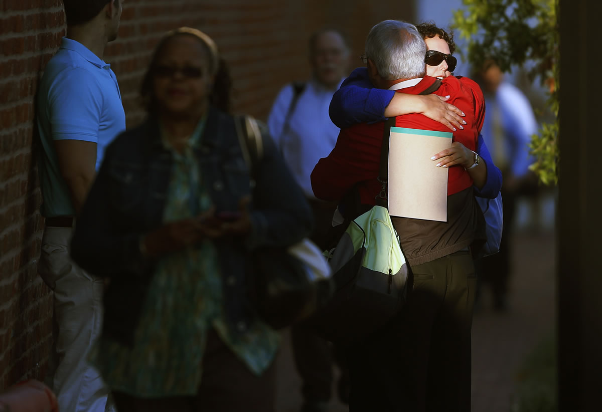 A woman hugs a man before entering the Washington Navy Yard as employees return to work Thursday.