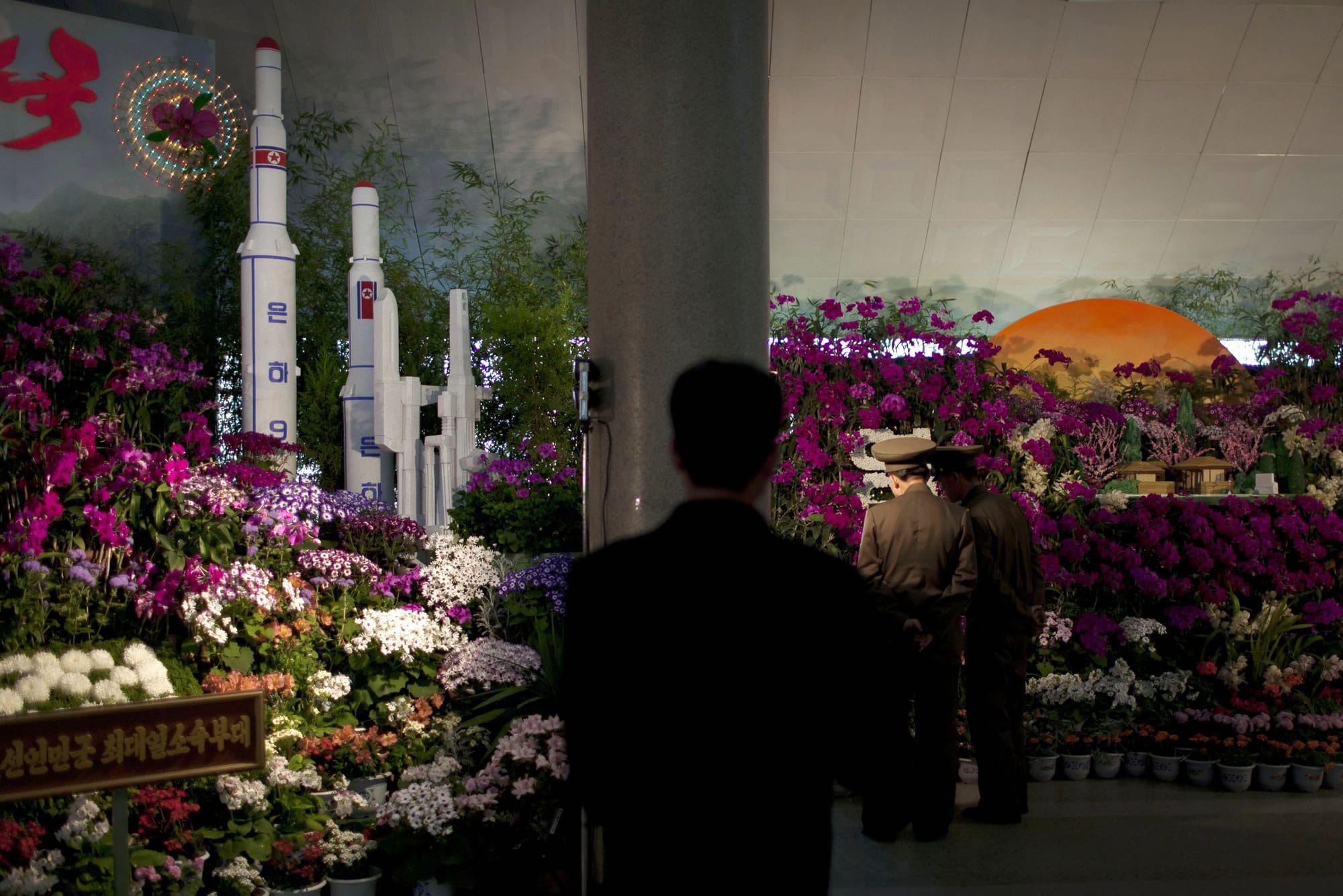 Two military officers admire displays at a flower show featuring thousands of Kimilsungia flowers, named after the late leader Kim Il Sung, while models of rockets and missiles are also exhibited in Pyongyang, North Korea, on Friday.