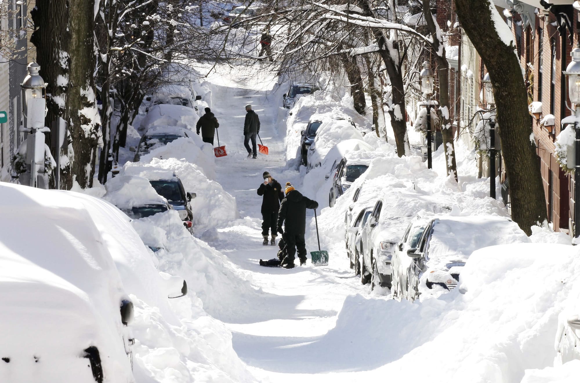 People dig out their cars Sunday on a Boston street. A storm left the New York-to-Boston corridor shrouded in 1 to 3 feet of snow Saturday.