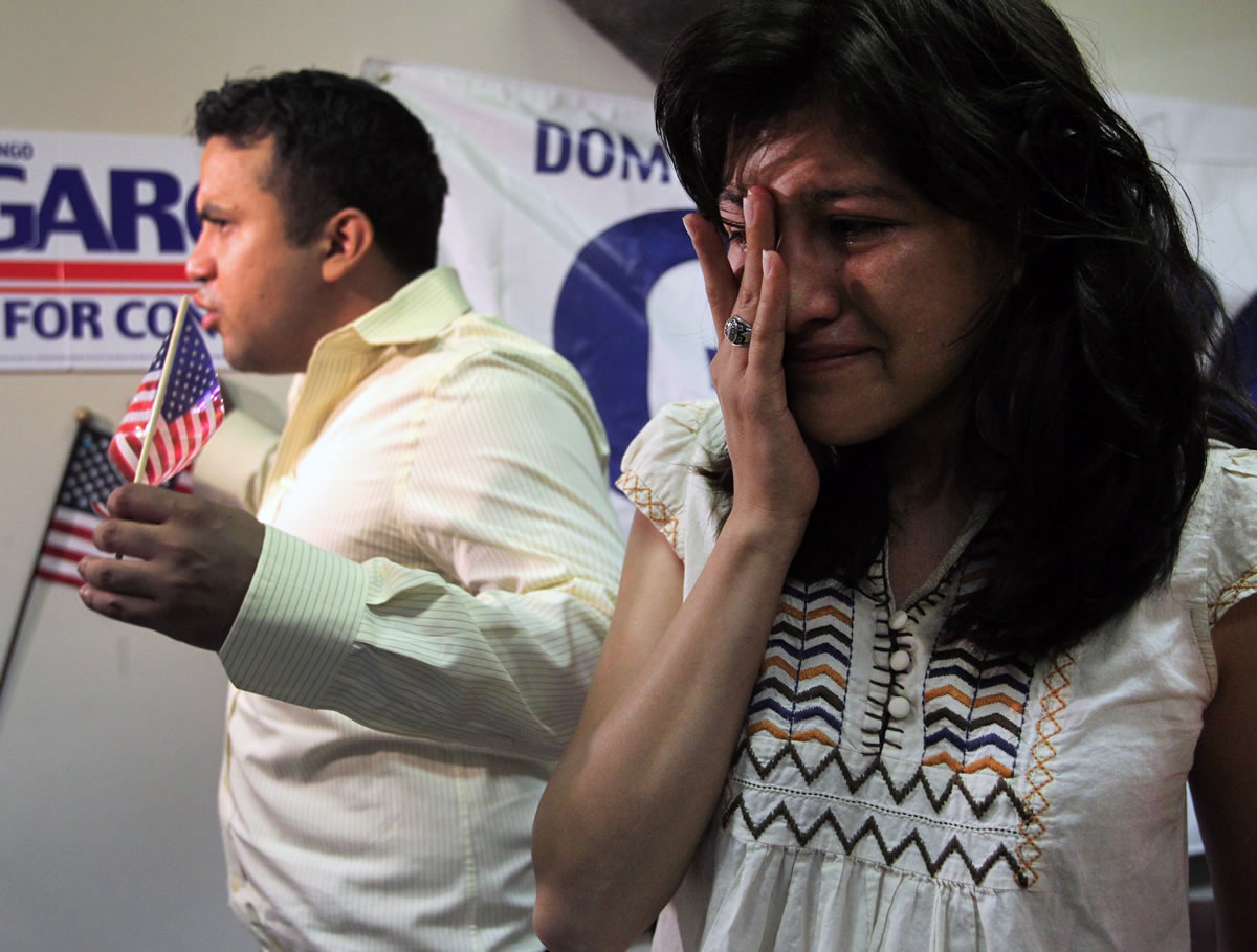 Lorena Tule-Romain, right, wipes tears away as Ramiro Luna, rear, talks to reporters following an announcement on the new U.S. immigration policy at the offices of Domingo Garcia in Oak Cliff, Texas on Friday, June 15, 2012. President Barack Obama eased enforcement of immigration laws Friday, offering a chance for hundreds of thousands of younger illegal immigrants to stay in the country and work.