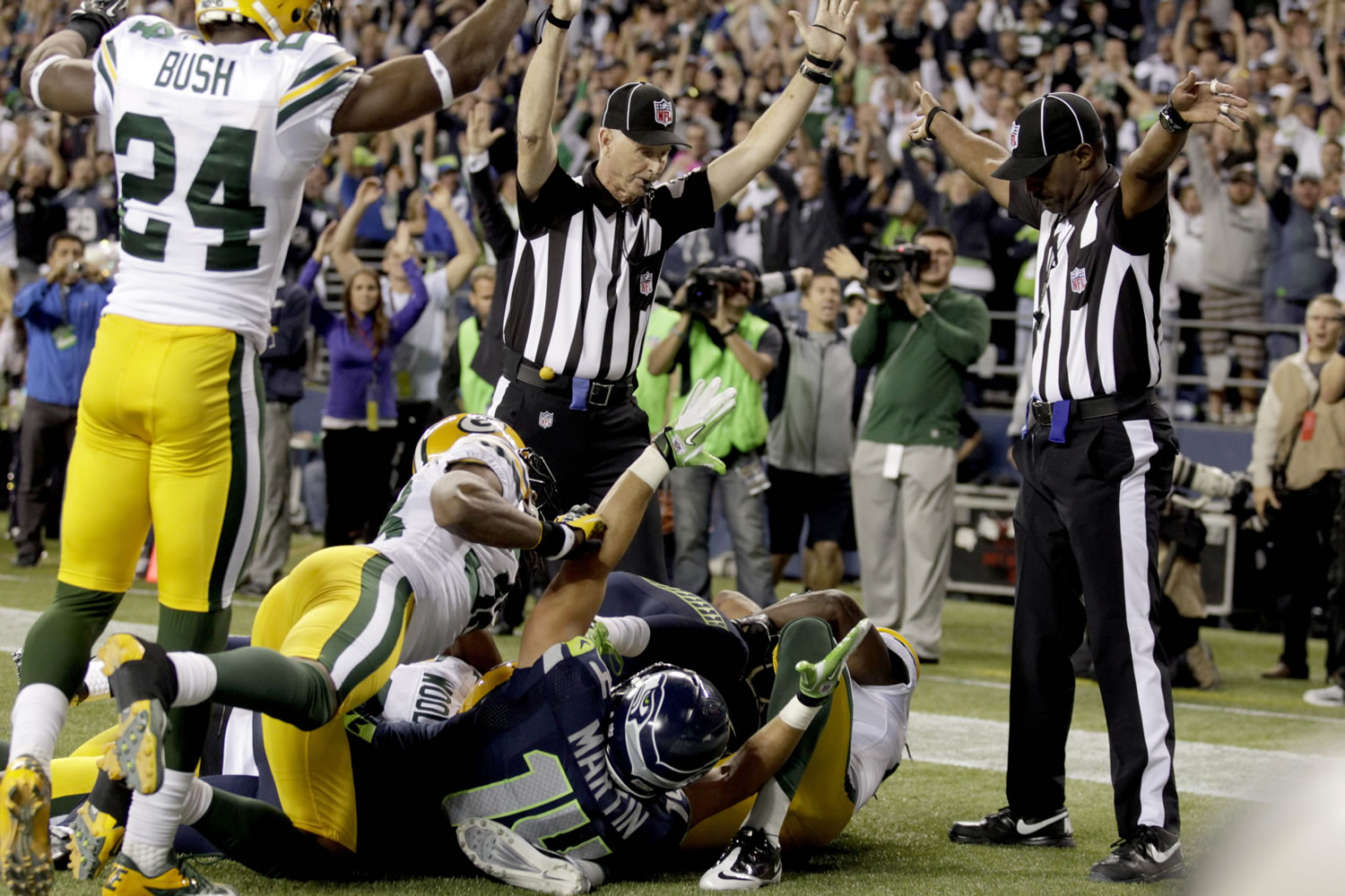 One official signals a touchdown, left, while the other one isn't sure on the final play of Monday's game. After video review, it was ruled Seattle's Golden Tate came up with the ball for the game-winning score.