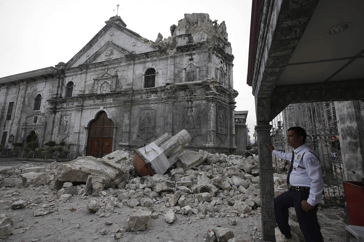 A private guard stands near the damaged Basilica of the Holy Child in Cebu, Philippines, following a 7.2-magnitude earthquake.