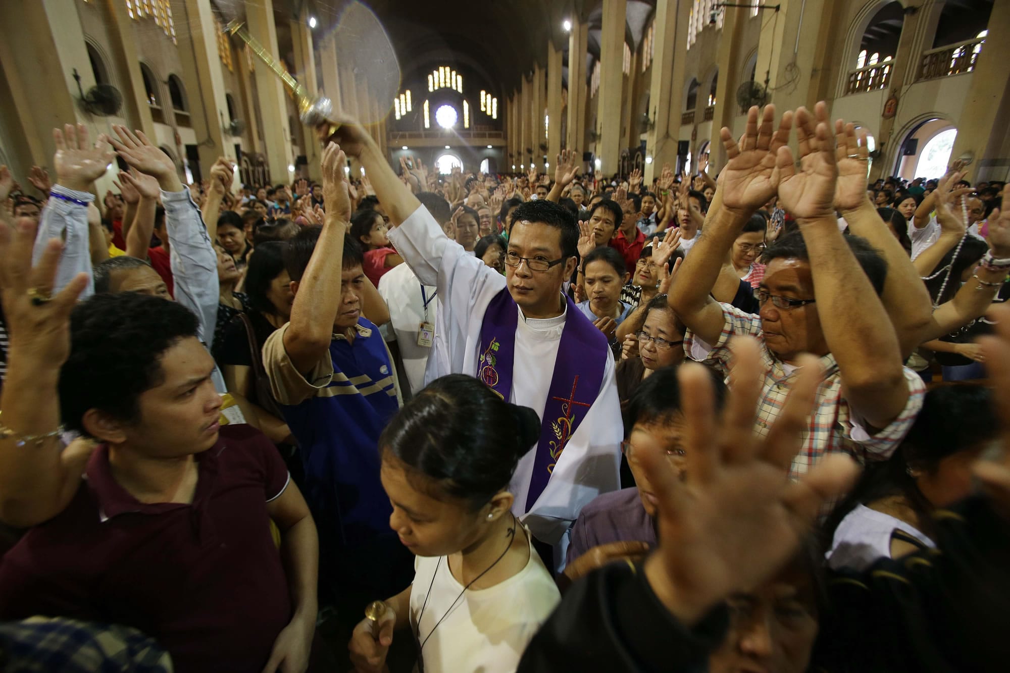 Filipino Catholic Priest Victorino Cueto, center, sprinkles holy water on devotees during a mass Sunday at the Shrine of Our Lady of Perpetual Help in suburban Paranaque, south of Manila, Philippines.