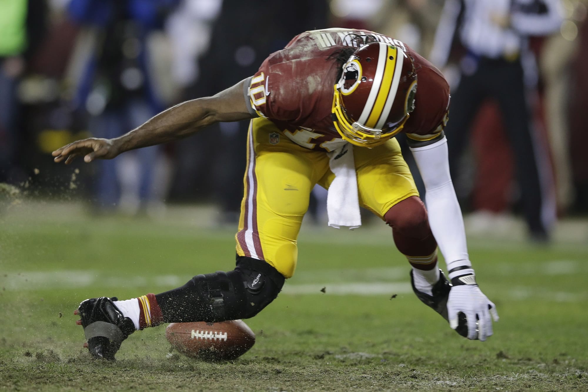 Washington Redskins quarterback Robert Griffin III twists his knees as he reaches for a loose ball after a low snap during the second half Sunday.