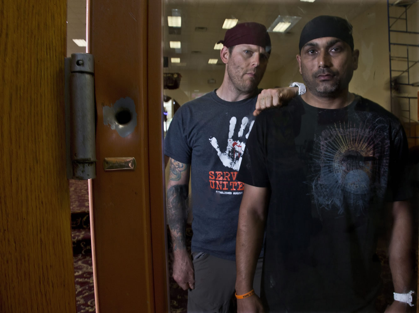 Pardeep Kaleka, right, and Arno Michaelis stand next to a bullet hole Wednesday at the Sikh Temple of Wisconsin in Oak Creek, Wis.