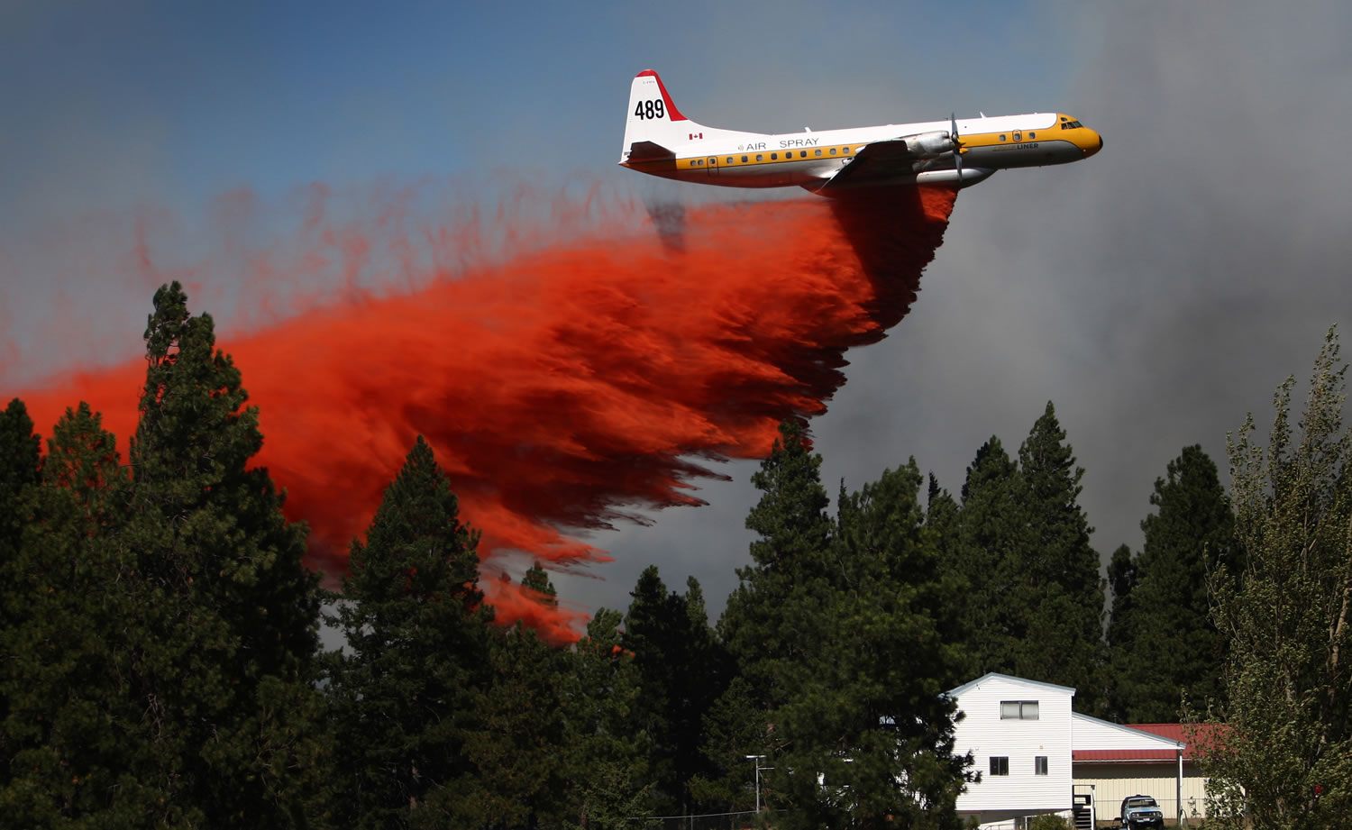 A plane drops retardant to create a fire break at the Sunlight Waters housing development Tuesday near Cle Elum. About 800 people were assigned to fight the Taylor Bridge fire, about 75 miles east of Seattle.