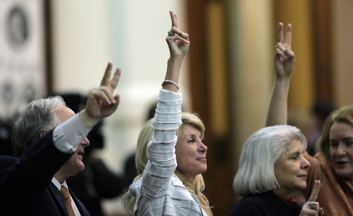 Sen. Wendy Davis, D-Fort Worth, center, holds up two fingers to signal a No vote as the session where they tried to filibuster an abortion bill draws to a close Tuesday in Austin, Texas.