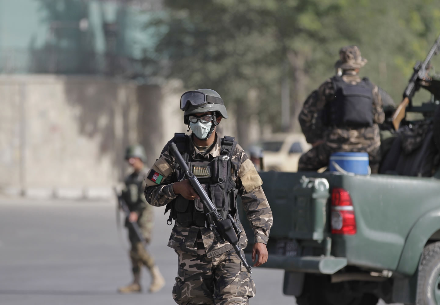 Afghan security and intelligence officers stand guard near the entrance gate of the presidential palace in Kabul, Afghanistan, on Tuesday. Suicide attackers blew up a car bomb and battled security forces outside Afghanistan's presidential palace Tuesday after infiltrating one of the most secure areas of the capital.