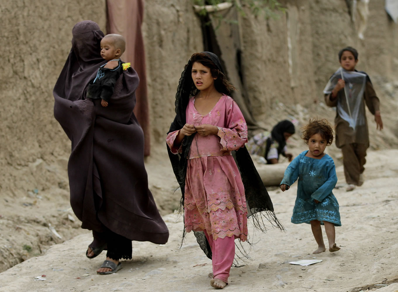 Displaced Afghans walks near their temporary homes on the outskirts of Kabul, Afghanistan, on Tuesday