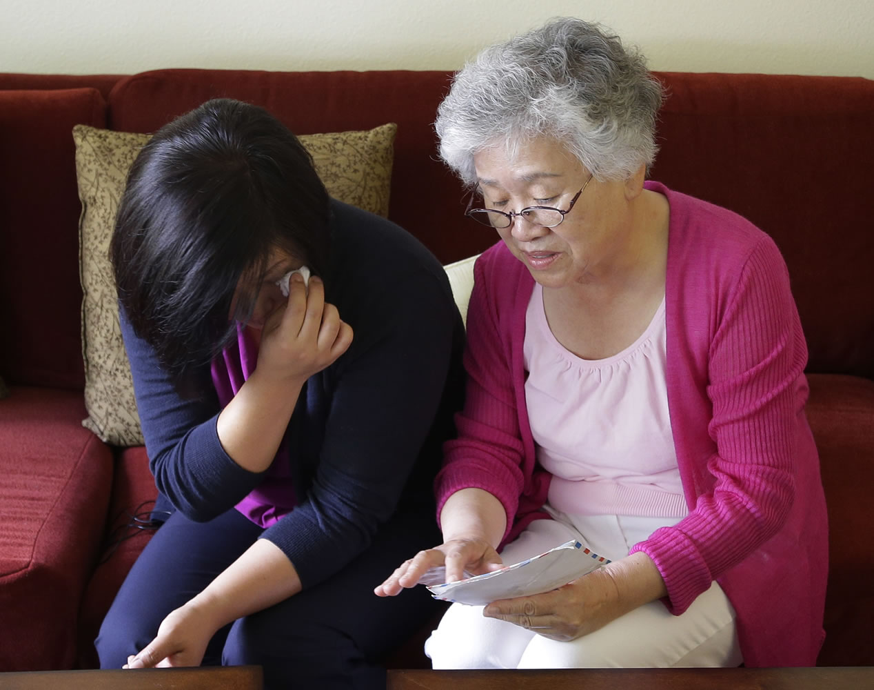 Terri Chung, left, and her mother, Myunghee Bae, right, look at a letter sent from their brother and son, Kenneth Bae, as they sit in Bae's home Aug. 7 in Lynnwood.