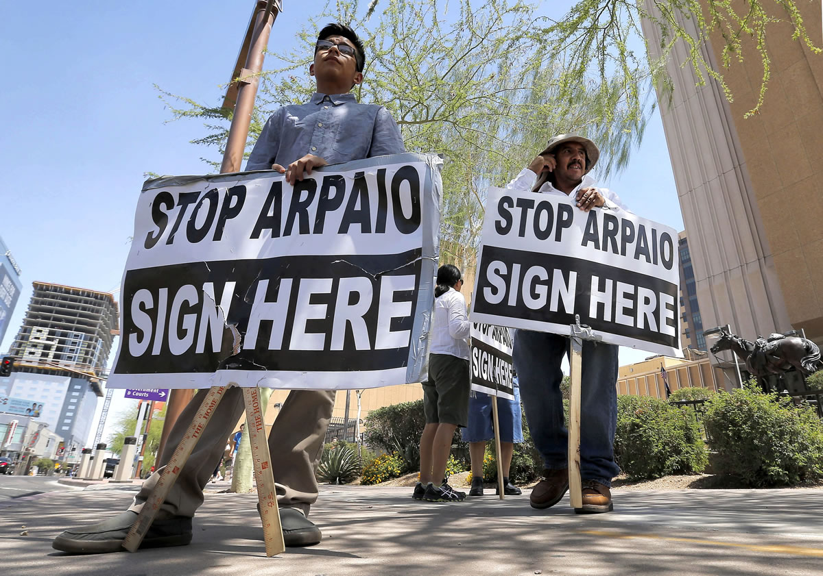 Simon Lopez, left, and Hiliaro Islas hold signs while trying to collect signatures in an effort to recall Maricopa County Sheriff Joe Arpaio on Wednesday in downtown Phoenix.