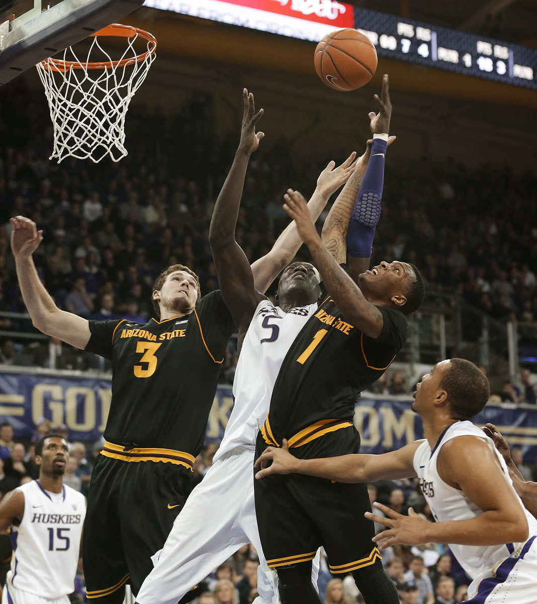 Washington's Aziz N'Diaye (5) tries to block a shot by Arizona State's Jahii Carson (1) as Arizona State's Eric Jacobsen (3) helps defend during the second half Saturday.