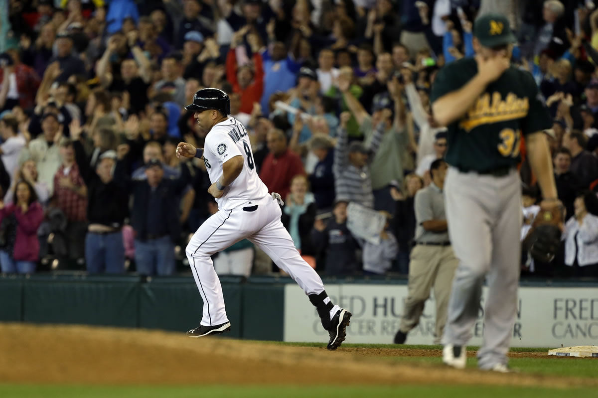 Seattle Mariners' Kendrys Morales, left, rounds the bases after he hit a walkoff three-run home run to give the Mariners a 6-3 win over the Oakland Athletics in the 10th inning Sunday.