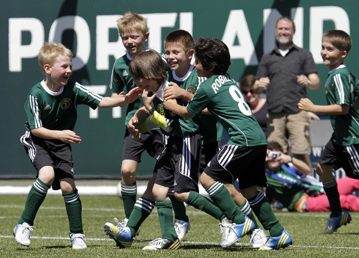 Don Ryan/The Associated Press
Atticus Lane-Dupre, 8, third from left, is congratulated by his teammates on the Green Machine soccer team after scoring the winning goal against the Portland Timbers. More than 3,000 fans came to Jeld-Wen Field to attend the Make-A-Wish matchup for a young cancer survivor.