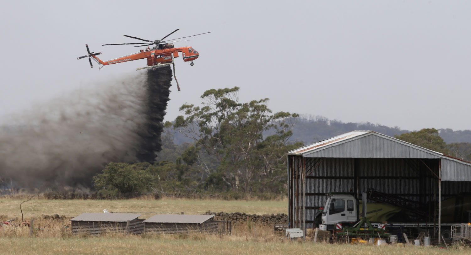 A Skycrane helicopter drops a load of water as it works to hold back a wildfire from the hamlet of Claredon in Victoria, Australia. More than 100 homes have been destroyed by the Christmas Day wildfire that tore through a stretch of coastline popular with tourists in southern Australia.