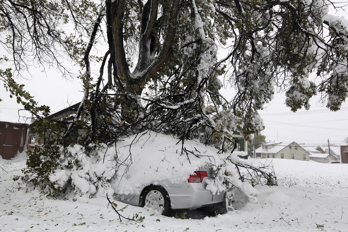 Broken tree branches cover a vehicle Saturday in Rapid City, S.D.  South Dakota emergency agencies are asking snowmobile operators in the Rapid City area to help find motorists stranded by an autumn storm. The National Weather Service says the storm dumped at least three and a half feet of wet, heavy snow in the Black Hills.