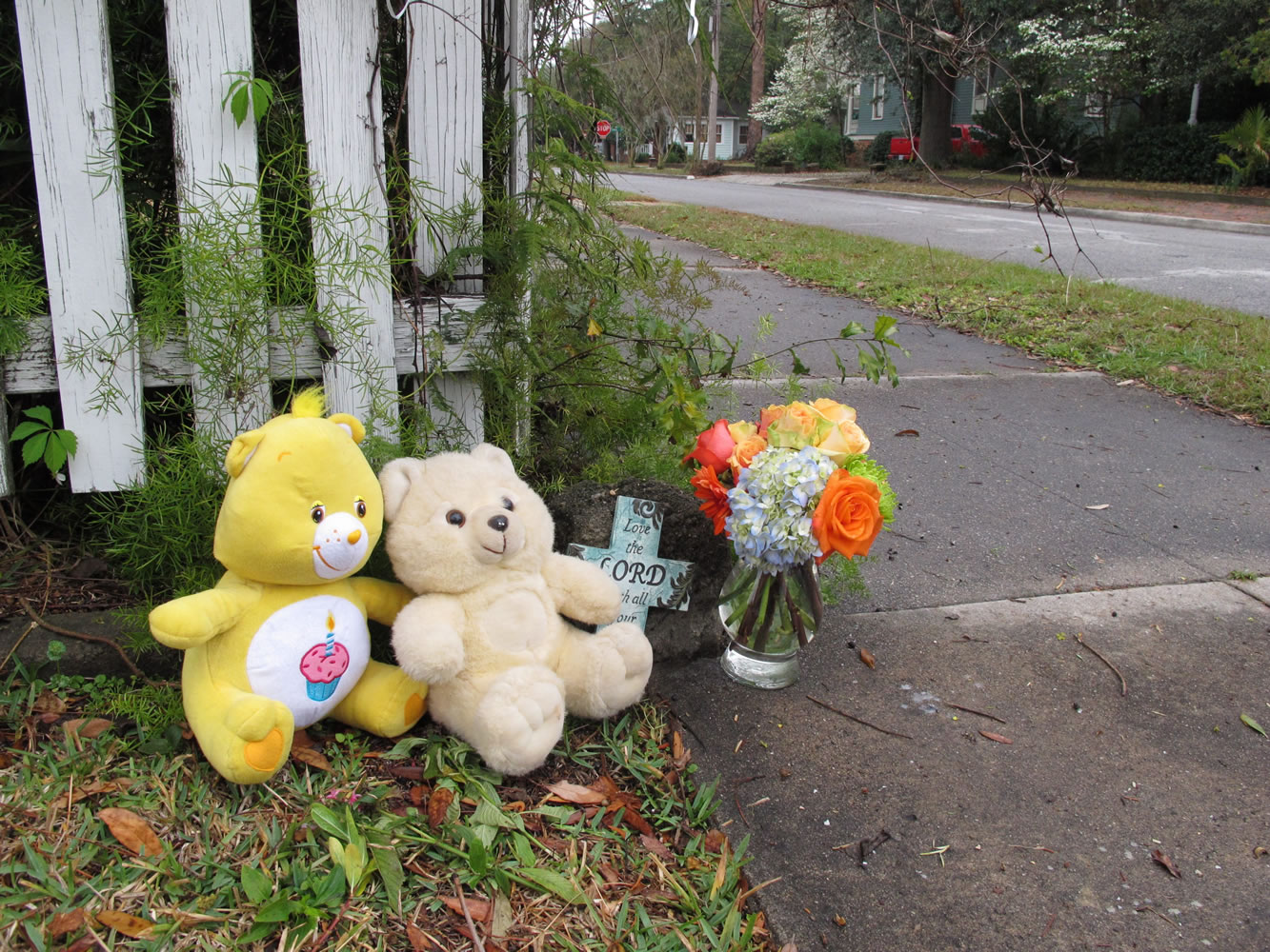 Two teddy bears, a commemorative cross and a vase of flowers sit on a street corner in Brunswick, Ga. on Saturday near where a 13-month-old baby was fatally shot in his stroller two days earlier.