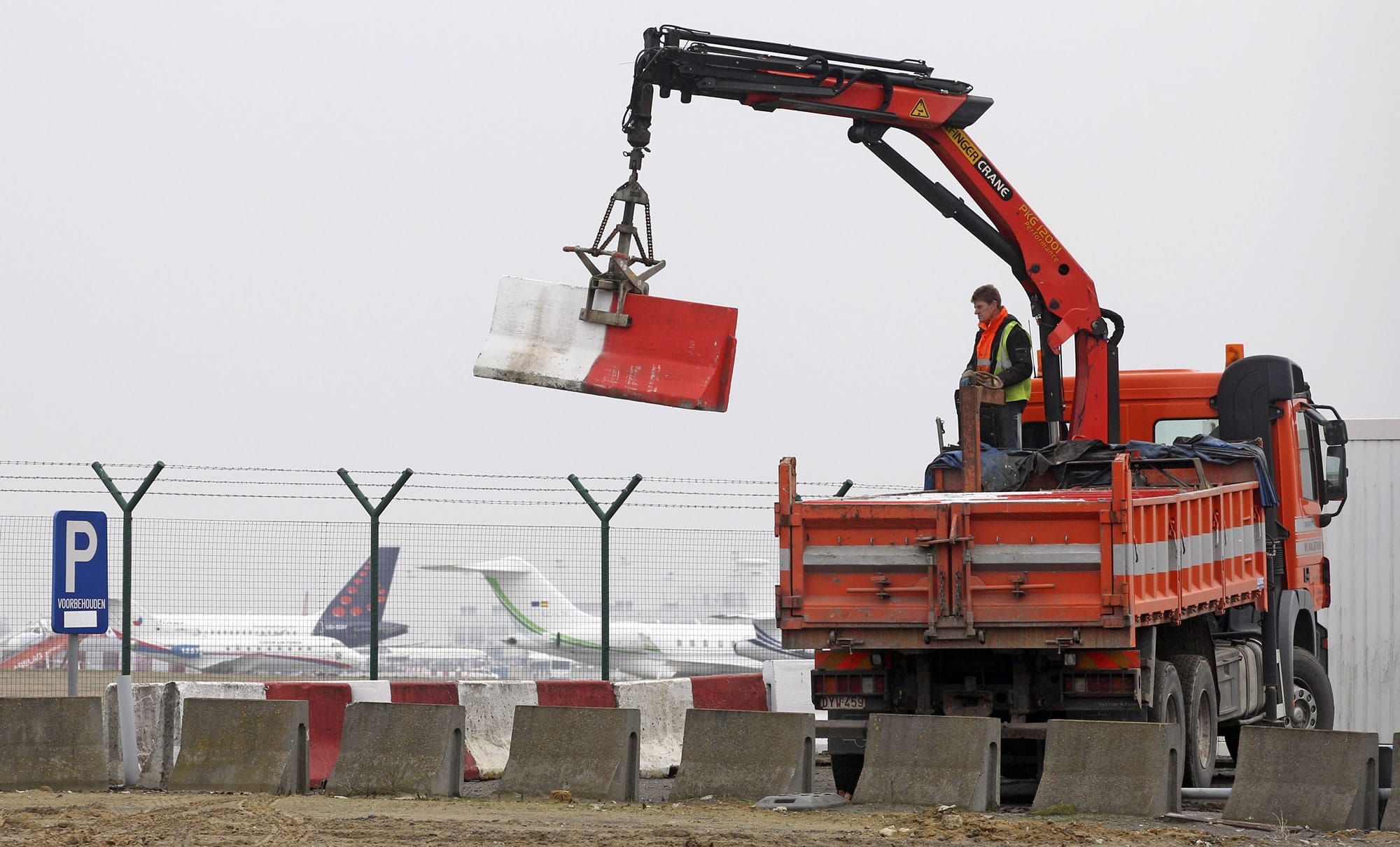 Workers place concrete blocks to block access to a security fence next to the tarmac at Brussels international airport Feb.