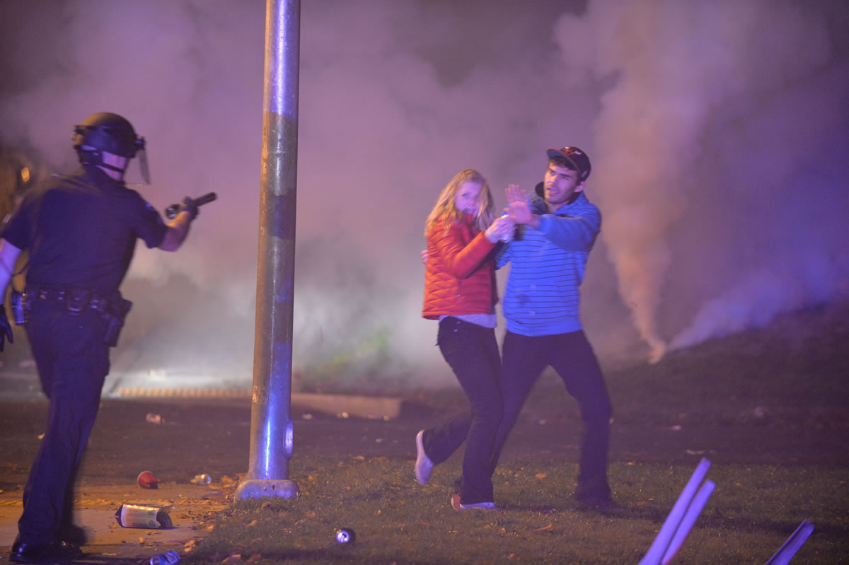 A Bellingham police officer warns people to leave the area after pepper spray was used by law enforcement officers to disperse hundreds of drunk, bottle-throwing college students who rioted along streets north of the Western Washington University campus Saturday in Bellingham.