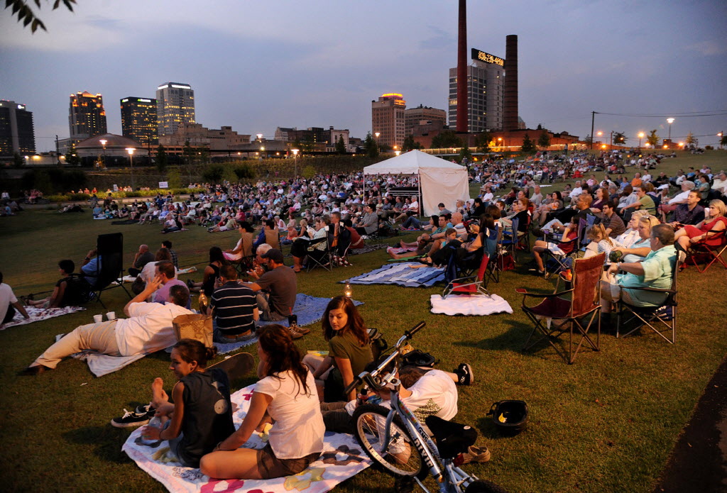 People sit on a hillside during a performance by the Alabama Symphony Orchestra in Railroad Park in Birmingham, Ala.