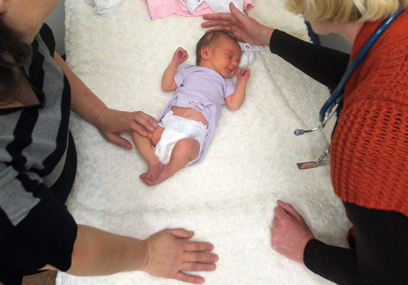 A family nurse practitioner, right, examines a newborn girl accompanied by her mother in Portland in June 2012.