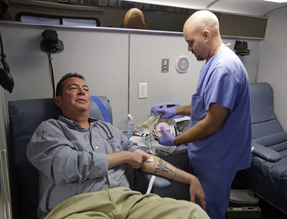 Technician Greg Snyder, right, finishes up a blood draw from Chris Page after he donated blood in an Indiana Blood Center Bloodmobile in Indianapolis. The Indiana Blood Center announced in June 2013 that it would reduce its mobile operations, close a donor center and cutting other costs because demand from hospitals had fallen 24 percent from the previous year.