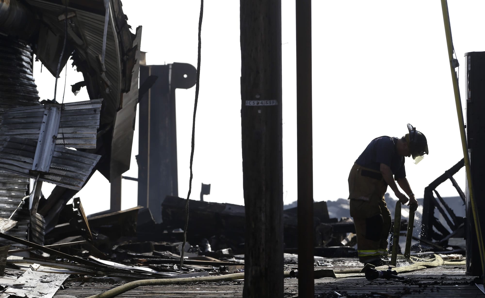 A firefighter disconnects two hoses the morning after a fire burned a large portion of the Seaside Park boardwalk, Friday in Seaside Park, N.J.