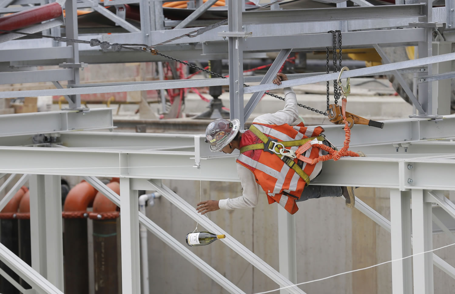 A worker positions a bottle of Washington white wine on a rope above Bertha.