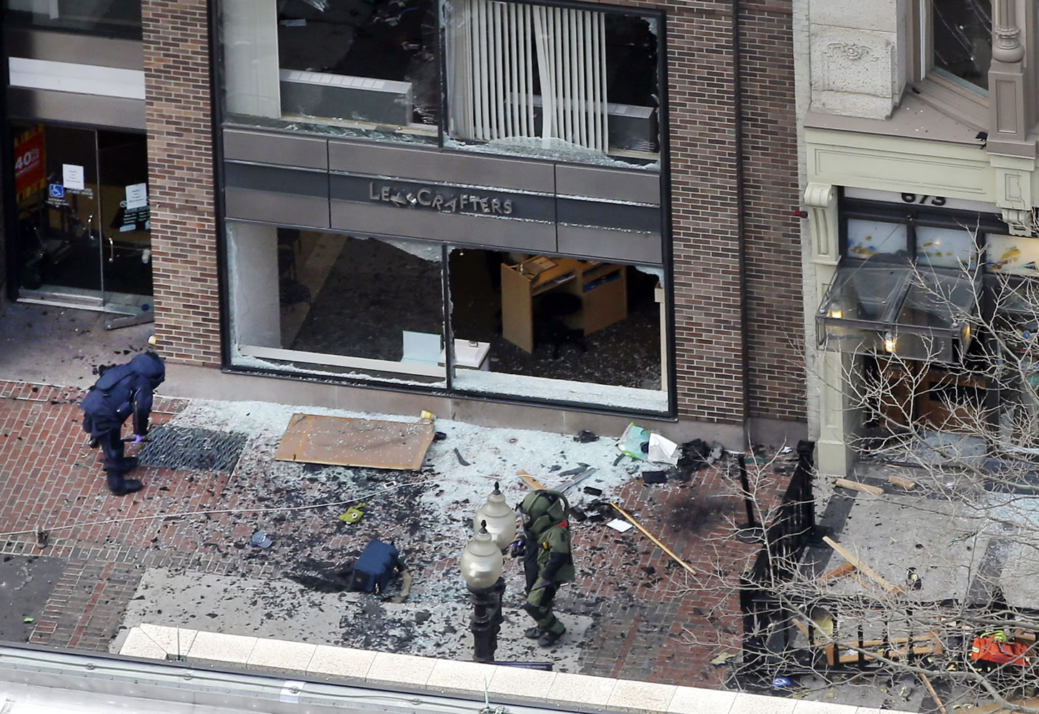 One of the blast sites on Boylston Street near the finish line of the 2013 Boston Marathon is investigated by two people in protective suits in the wake of two blasts in Boston on Monday.