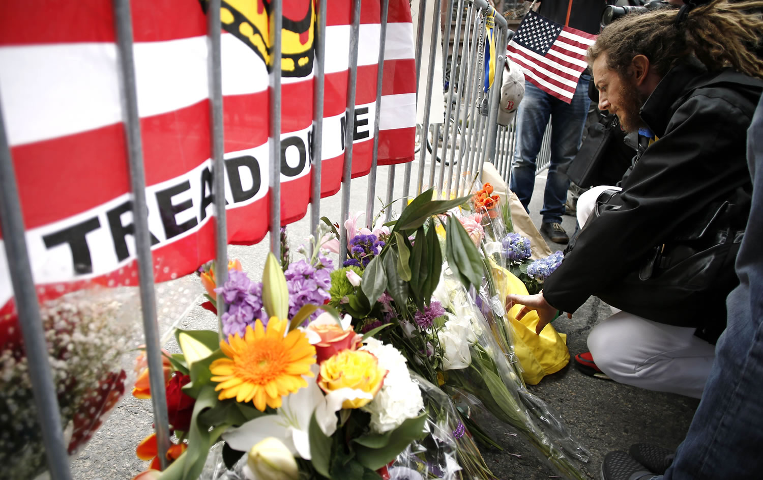 A mourner places a note with flowers at a police barricade near the finish line of the Boston Marathon in Boston on Tuesday.