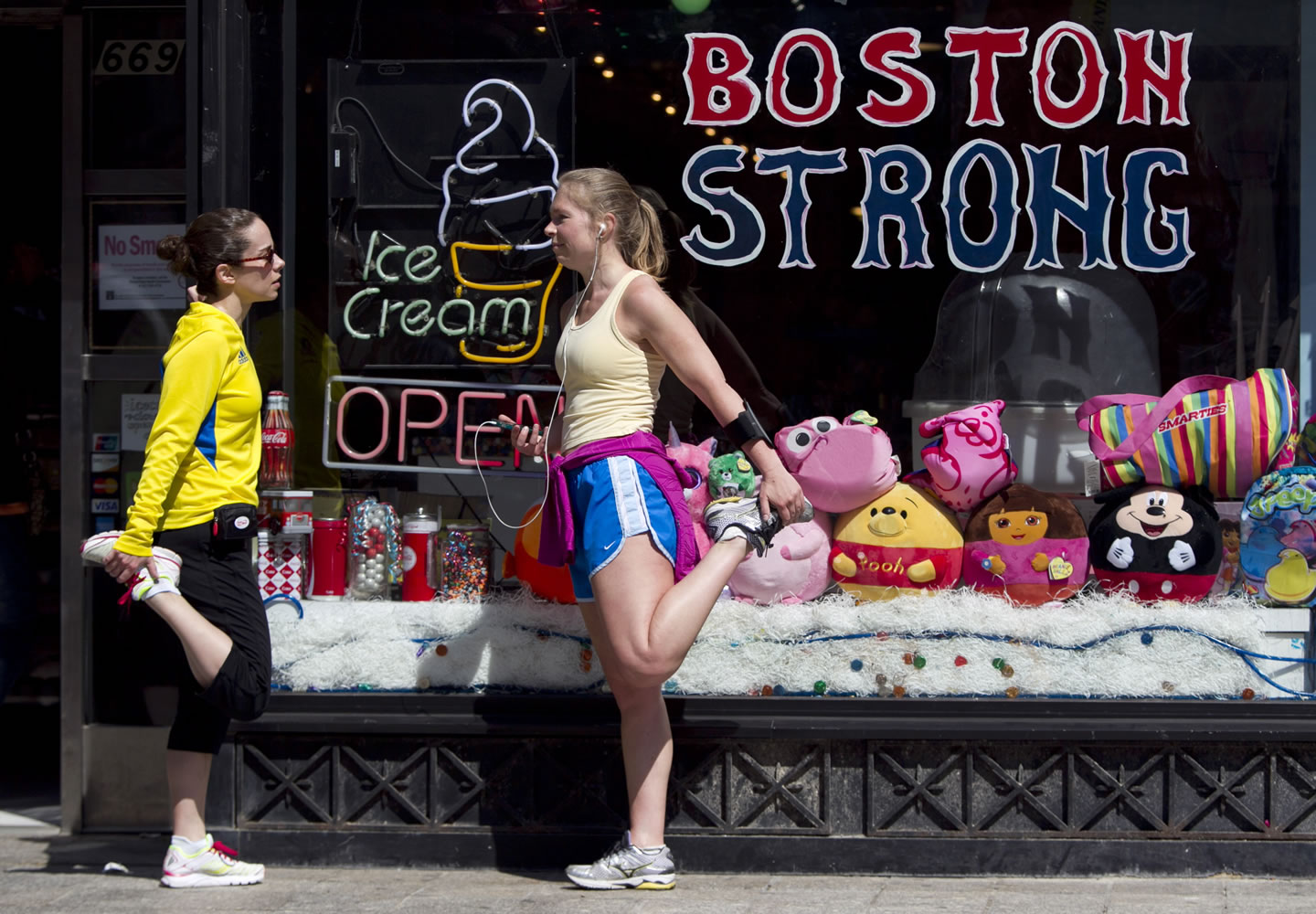 Runners Linda DePoto, left, of Brighton, Mass., and Lauren Cain, of Brookline, Mass., stretch Saturday after crossing the finish line of the Boston Marathon in Boston, Mass.