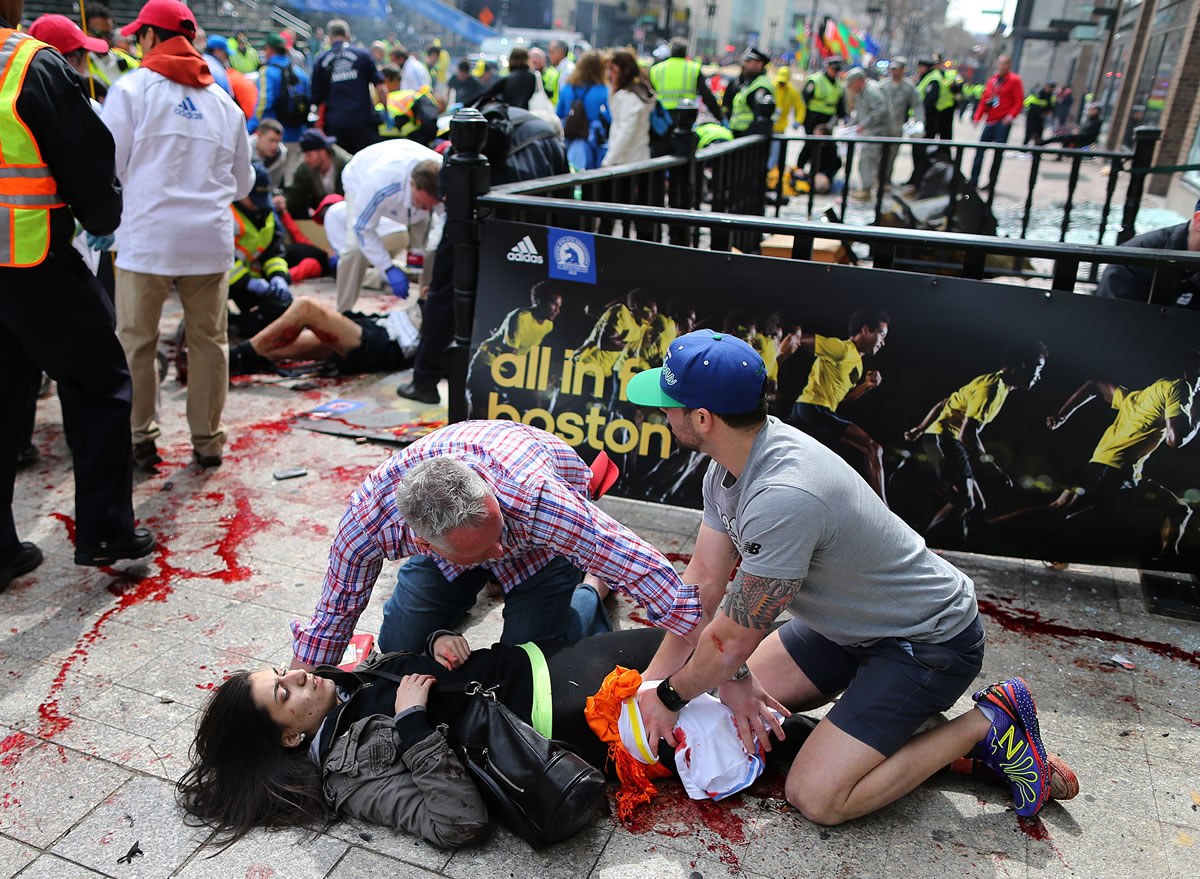 An injured woman is tended to at the finish line of the Boston Marathon after two bombs exploded in Boston.