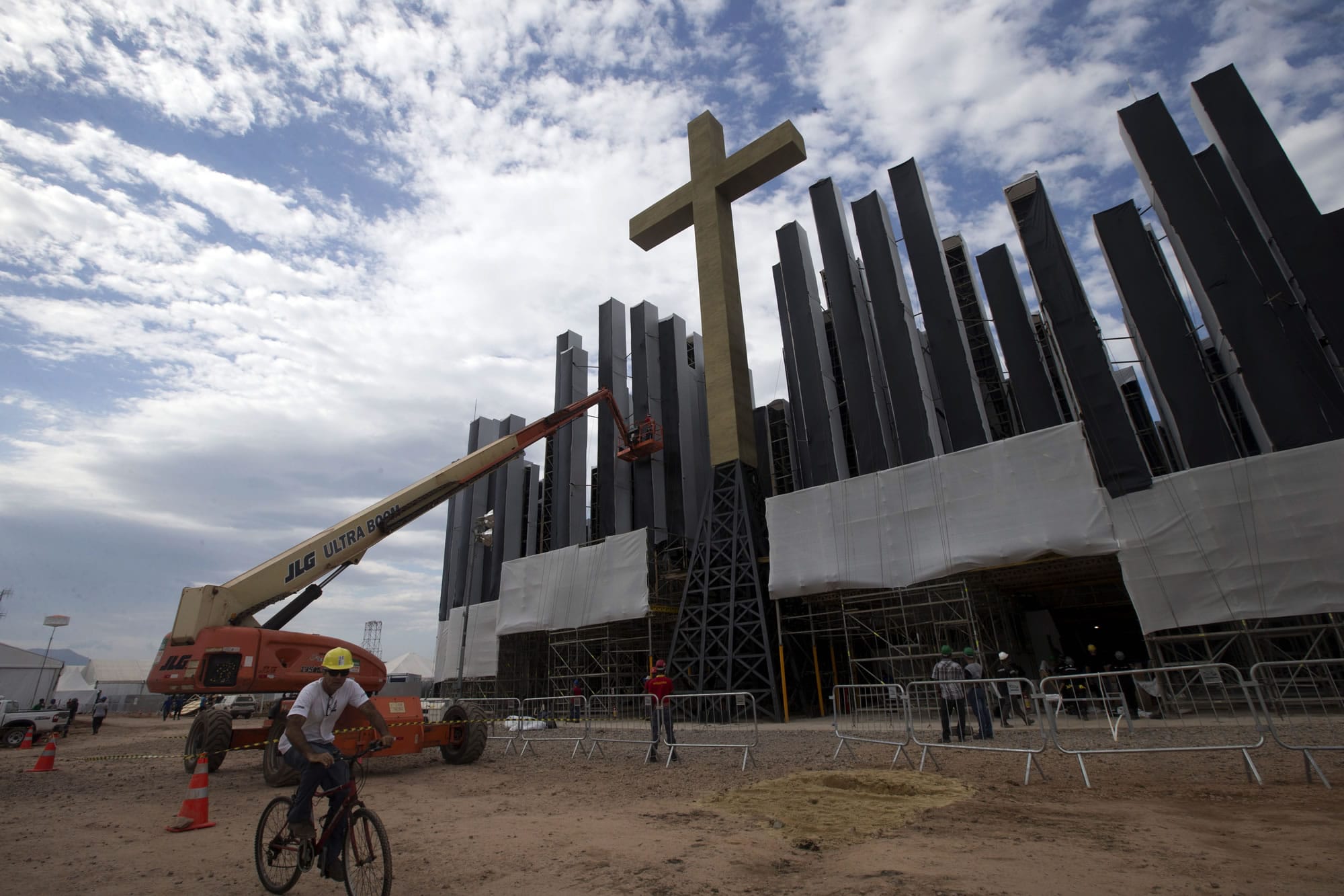 A worker rides a bicycle Sunday as the stage where Pope Francis will deliver mass next week is being prepared in Guaratiba, some 40 km. south of Rio de Janeiro, Brazil.
