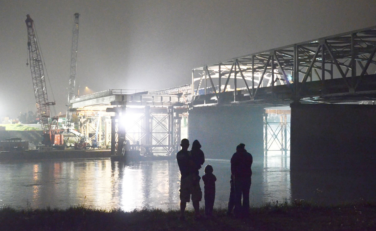 The Clint and Jolie Boerner family of Stanwood watch workers cut away the anchor bolts to the temporary span Saturday night on the I-5 Bridge over the Skagit River.  The permanent repair span is to have been slid into place in rails early this morning. The Boerners brought their children to see the bridge when it collapsed in May and wanted them to see what had since transpired.