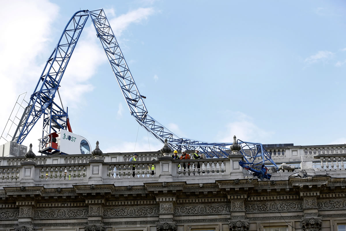 Workmen survey the damage caused by a crane brought down by high winds onto the roof of the Cabinet Office in Whitehall, near Downing Street in London on Monday.