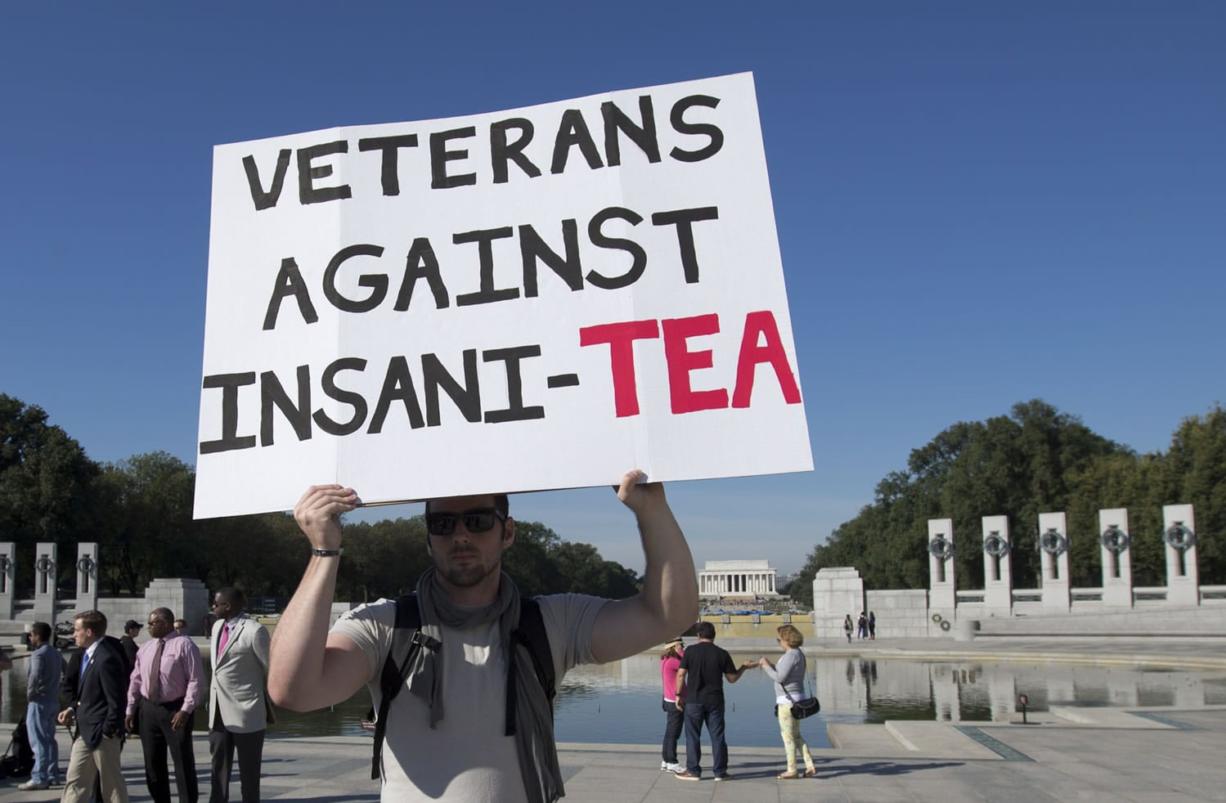 Army veteran David Roper of Alexandria, Va., holds a sign during a rally by the Military Coalition at the National World War II Memorial on Tuesday in Washington.