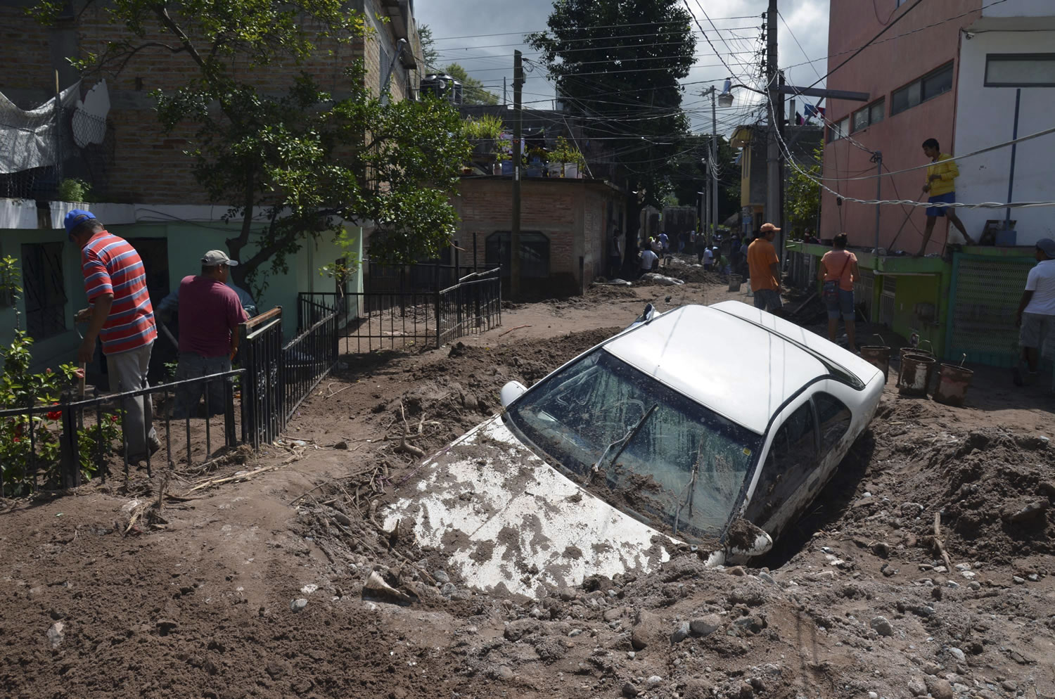 CORRECTS LAYS TO LIES-A car lies buried in mud after flooding triggered by Tropical Storm Manuel as residents try to clean up their neighborhood in Chilpancingo, Mexico, Thursday, Sept. 19, 2013.  Manuel, the same storm that devastated Acapulco, gained hurricane force and rolled into the northern state of Sinaloa on Thursday before starting to weaken.