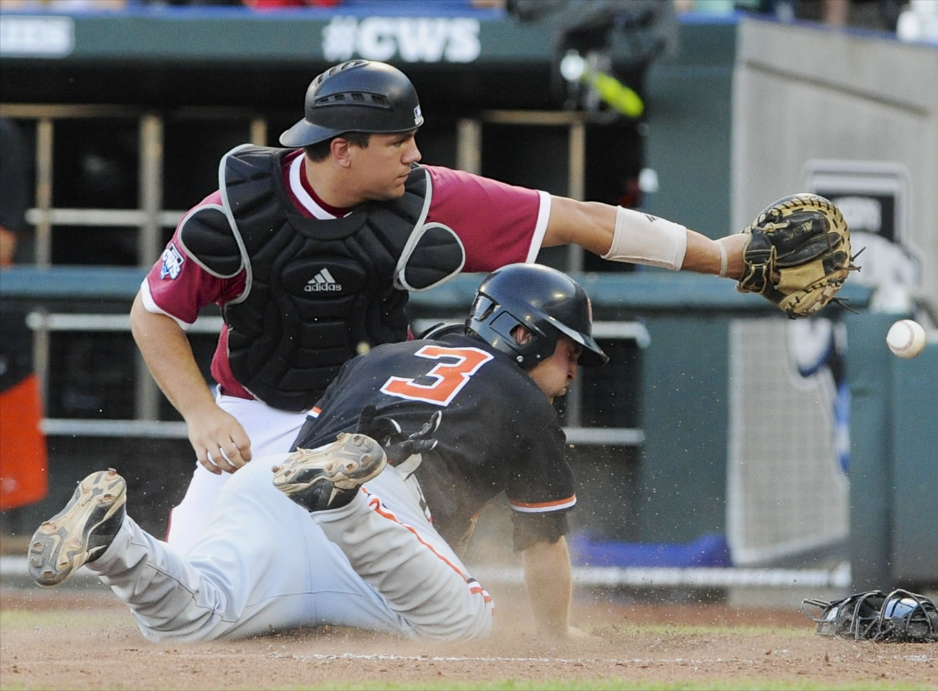 Oregon State's Kavin Keyes (3) scores at home plate as the ball gets away from Indiana catcher Kyle Schwarber on a sacrifice fly by Jake Rodriguez in the fourth inning of an NCAA College World Series elimination baseball game in Omaha, Neb., Wednesday, June 19, 2013.