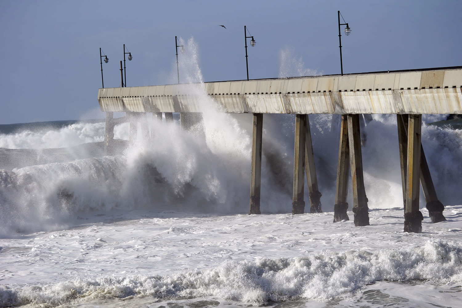 Waves crash on the municipal pier Friday in Pacifica, Calif. The National Weather Service says the biggest storm of the season should quiet down in the Sierra Nevada before kicking back up Saturday.