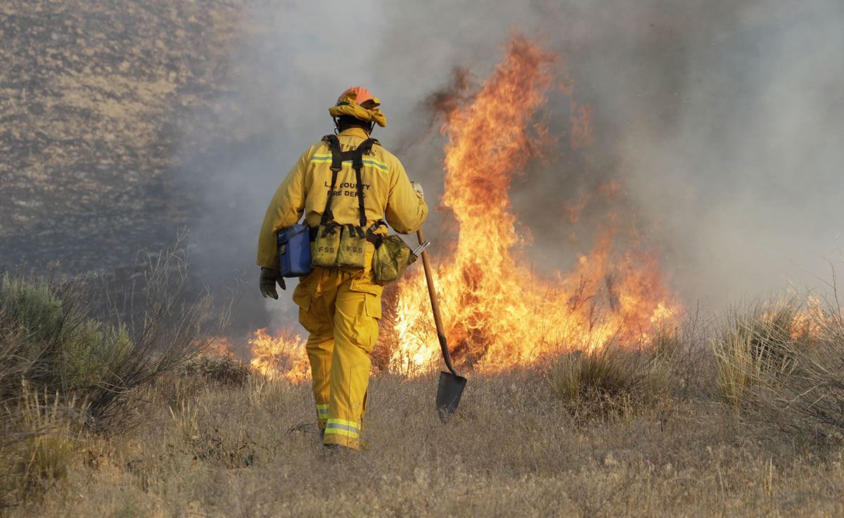A Los Angeles County firefighter approaches a fire along a road in what has been called the Powerhouse fire in Lake Hughes, Calif., early Sunday.