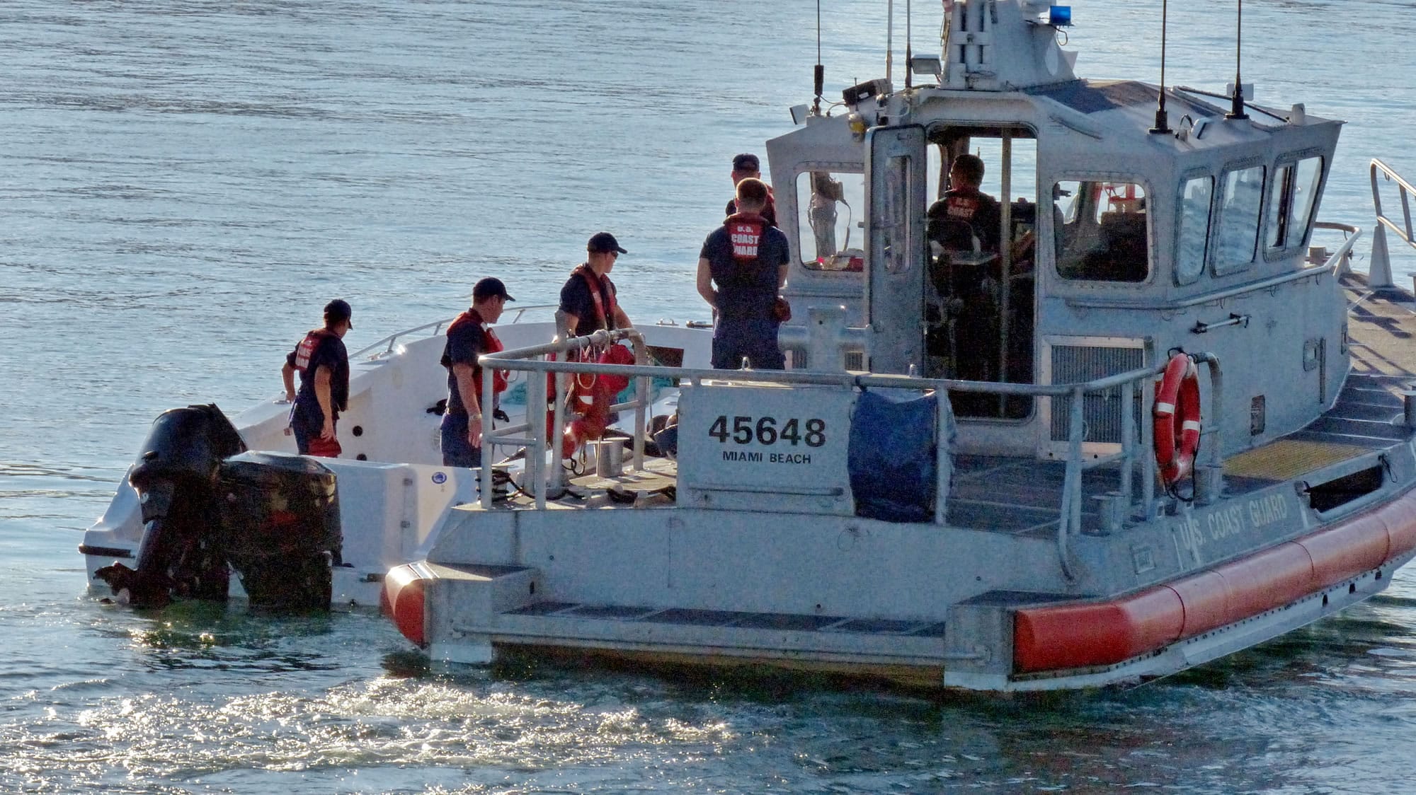U.S Coast Guard personnel investigate a vessel with a missing center console that capsized near Miami on Wednesday.