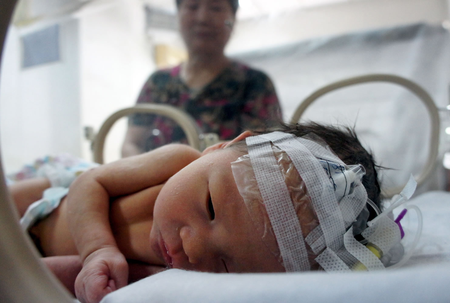 The baby who was rescued from a sewage pipe lies in an incubator Tuesday at a hospital in China's Zhejiang province.