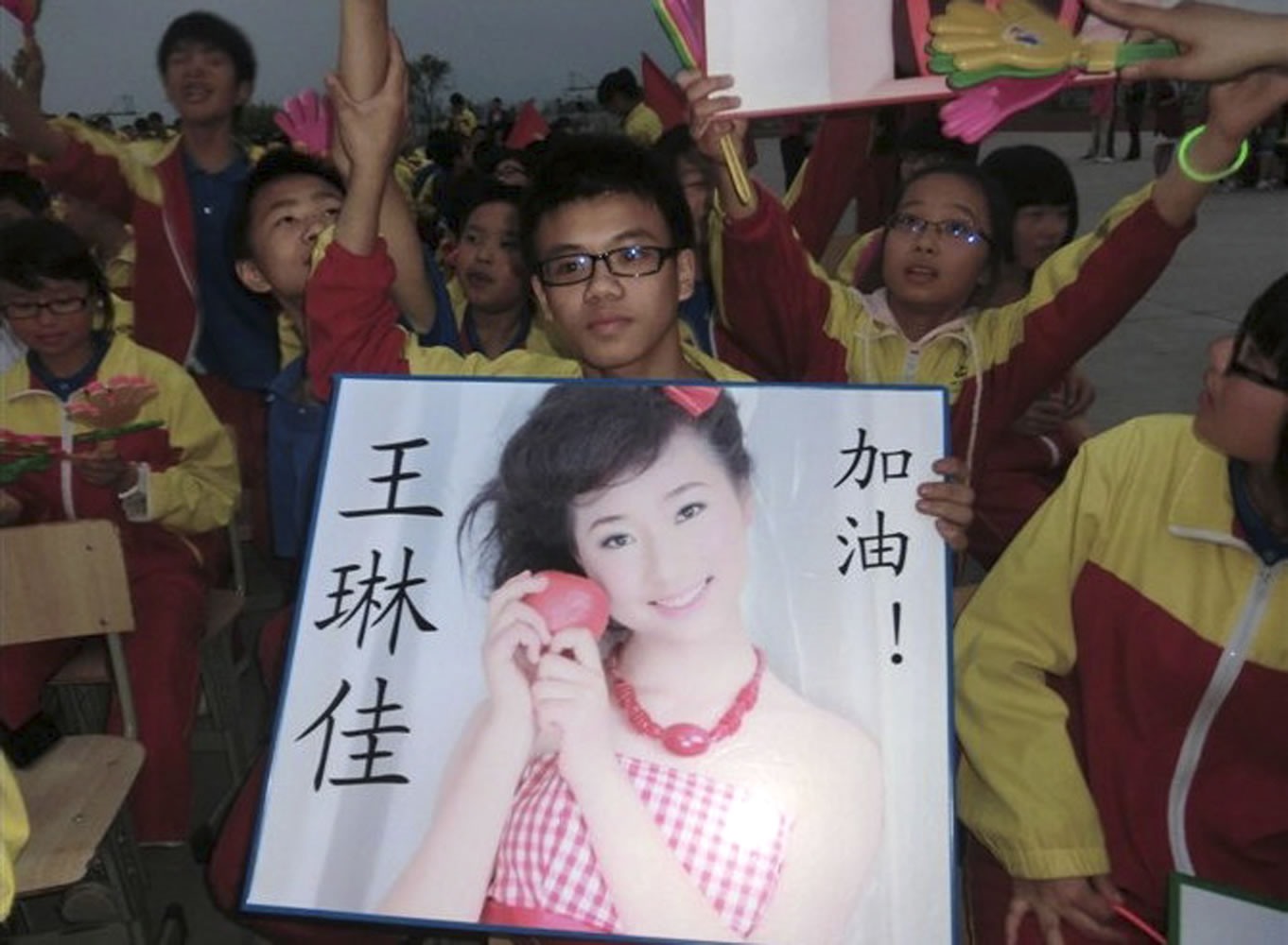 In this undated photo made available Monday, July 8, 2013, a supporter of Wang Linjia, holds up a photo of her with her name during a talent show at a school in Jiangshan city in eastern China's Zhejiang province. Chinese state media and Asiana Airlines have identified the two victims of the Asiana Airlines crash at San Francisco International Airport girls as Ye Mengyuan and Wang Linjia, students in Zhejiang, an affluent coastal province in eastern China.