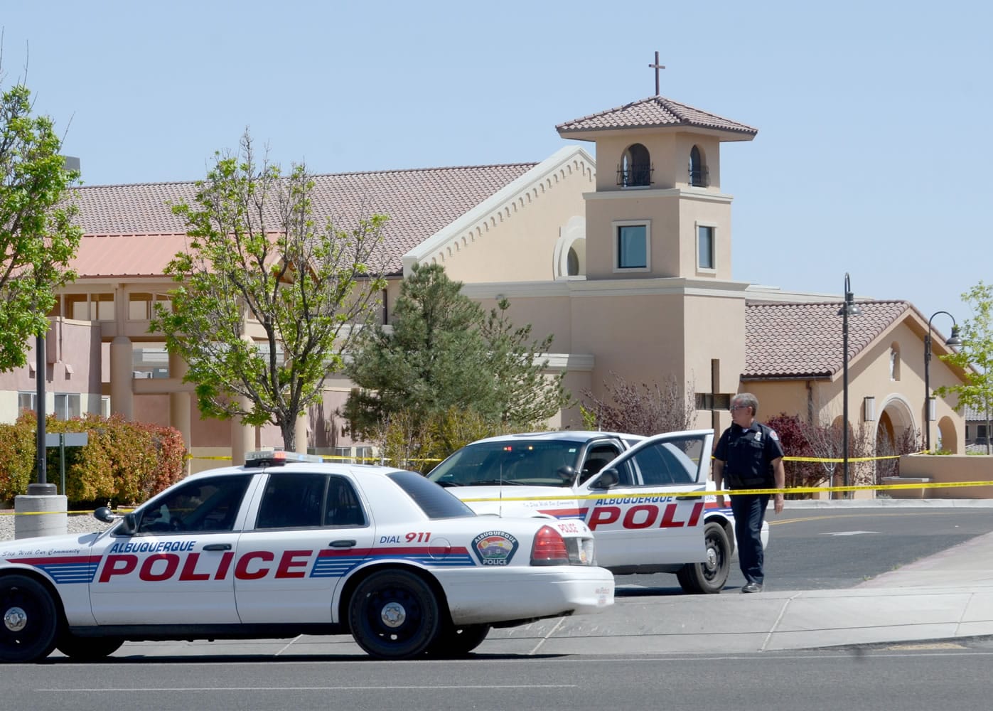 An Albuquerque Police officer walks behind the tape at St. Jude Thaddeus Catholic Church on Sunday in Albuquerque, N.M., the scene of a multiple stabbing at the conclusion of morning services.