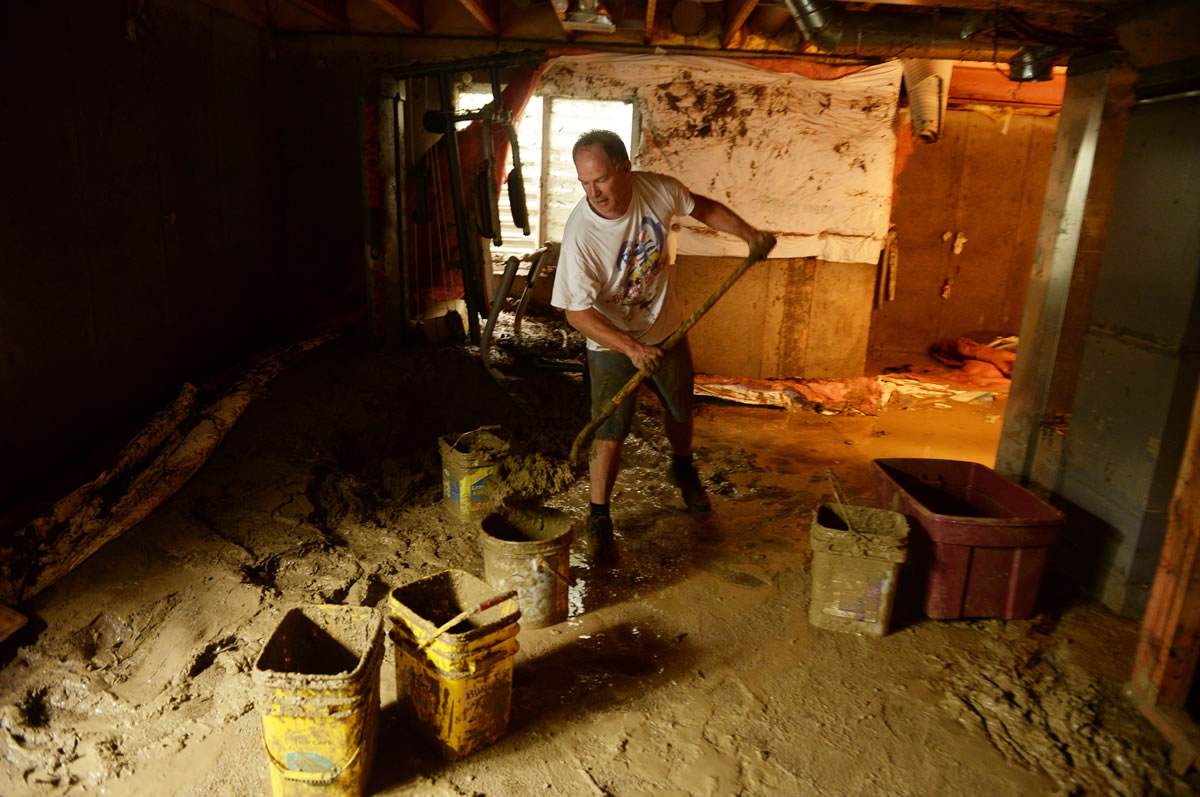 Mike Steinpach moves mud out from the basement of Stan McDonald's house damaged by flooding in Longmont, Colo., on Sunday.
